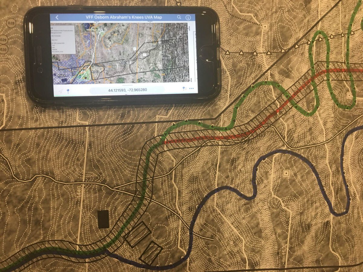 A smartphone displays a property map in the Avenza mapping app and rests on a paper map of the same property.