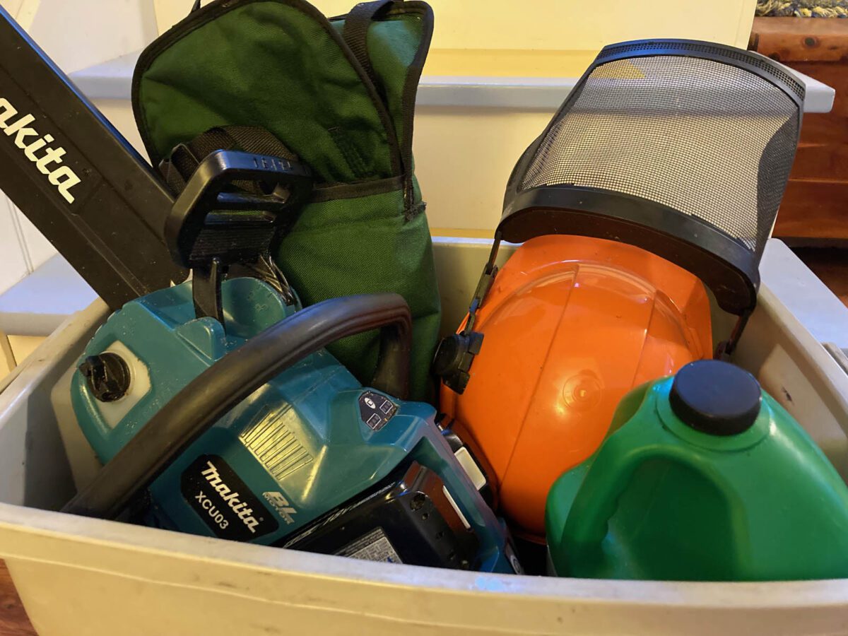 Battery-powered, vegetable-oil-lubricated chainsaw equipment in a plastic storage bin.