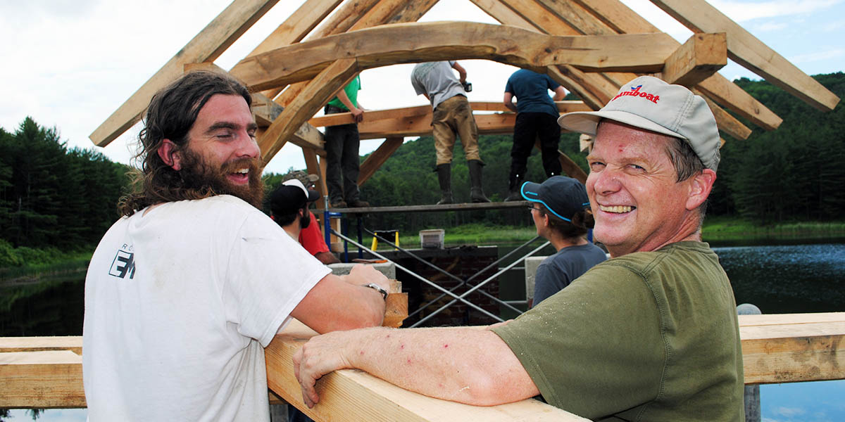 Two men carrying a beam at a timber framing event