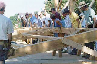 A group of people helping to lift a timber framed wall