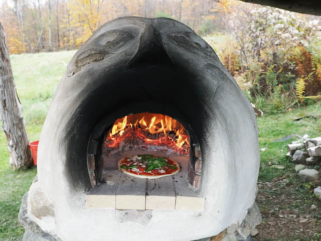 Durga, our earth oven, fires up another pizza.