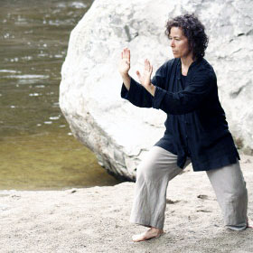 Woman practicing Tai Chi on a river bank