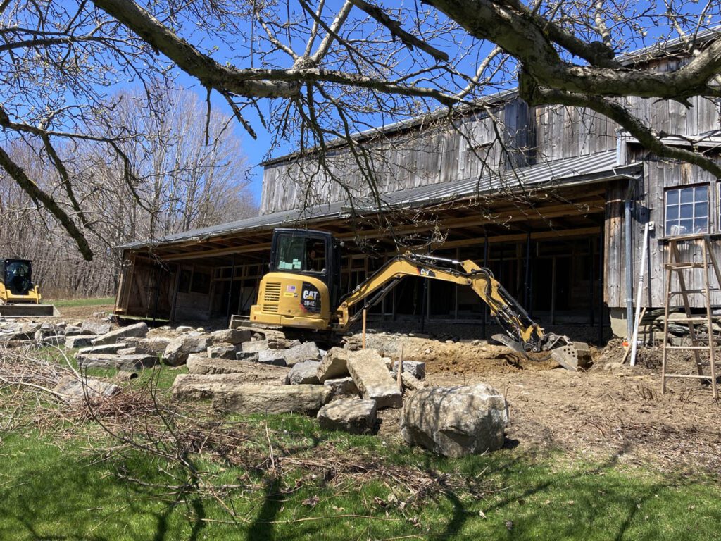 Excavator working on foundation of old barn.