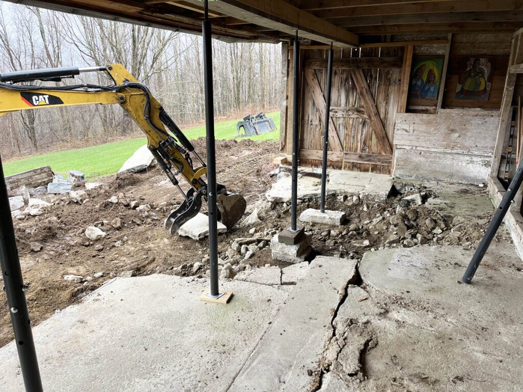 Excavator removing concrete floor from old barn.