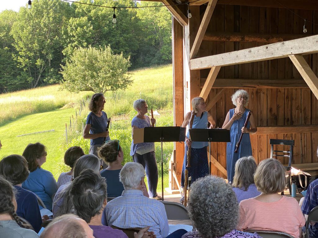musical performers facing audience in a barn.