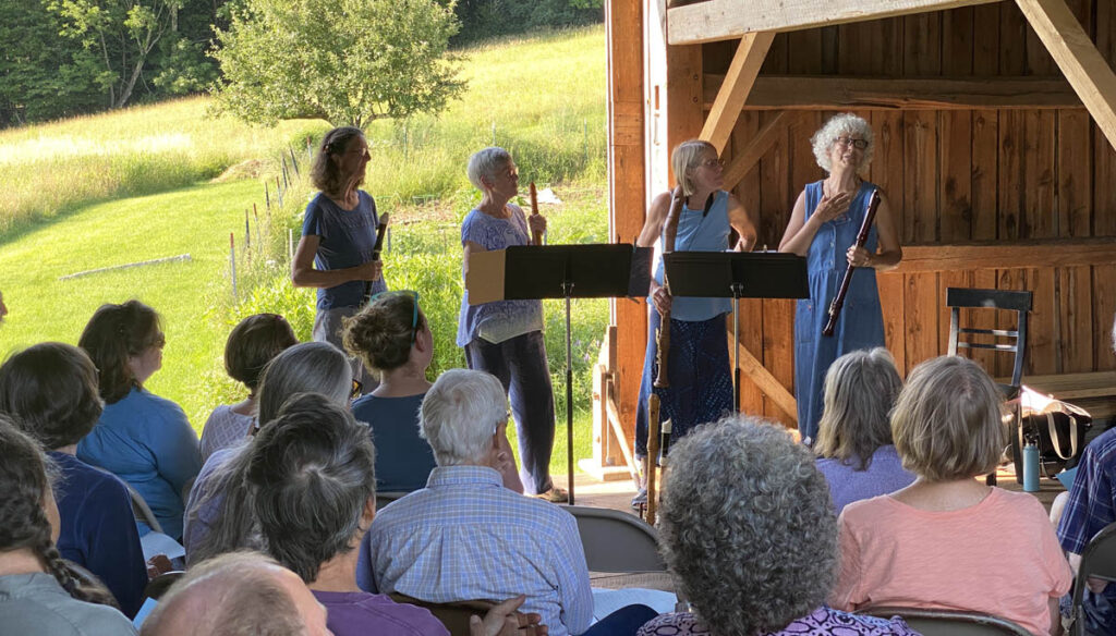musical performers facing audience in a barn.
