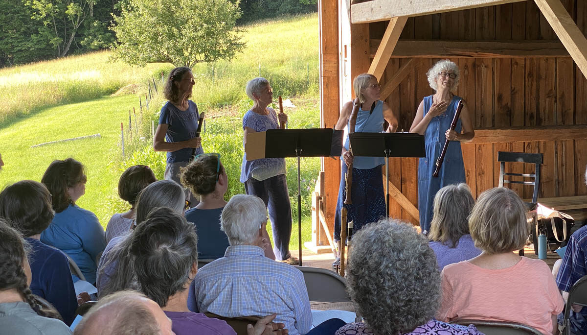 musical performers facing audience in a barn.